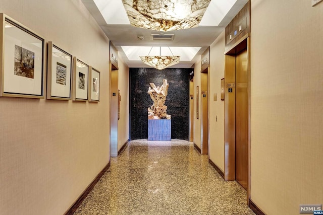 corridor featuring elevator and a notable chandelier