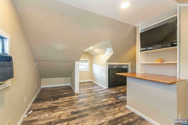 additional living space featuring dark wood-type flooring and lofted ceiling