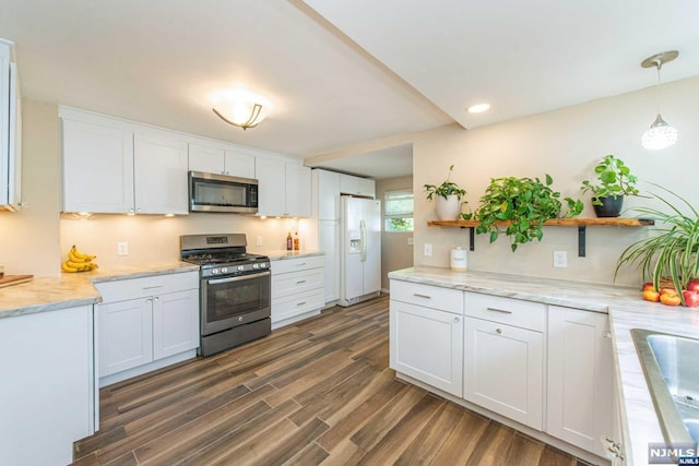 kitchen with appliances with stainless steel finishes, dark hardwood / wood-style floors, white cabinetry, and pendant lighting