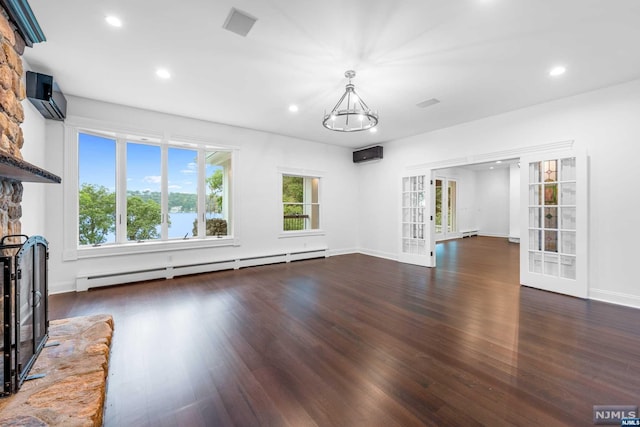 unfurnished living room featuring an inviting chandelier, french doors, an AC wall unit, dark hardwood / wood-style floors, and baseboard heating