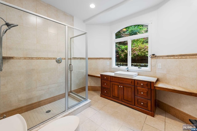 bathroom with tile patterned floors, vanity, tile walls, and walk in shower