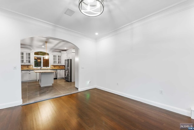 unfurnished living room featuring dark hardwood / wood-style flooring and crown molding