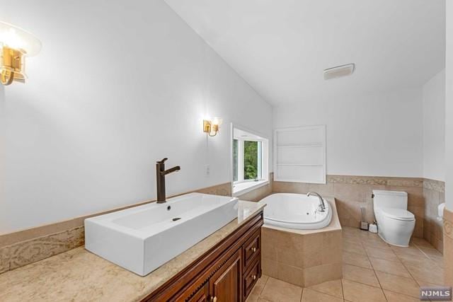 bathroom with tile patterned floors, vanity, tiled bath, toilet, and lofted ceiling