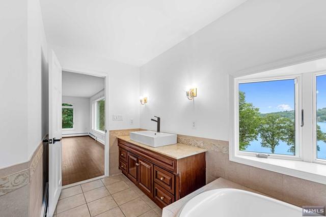 bathroom featuring tile patterned flooring, vanity, a tub to relax in, and tile walls