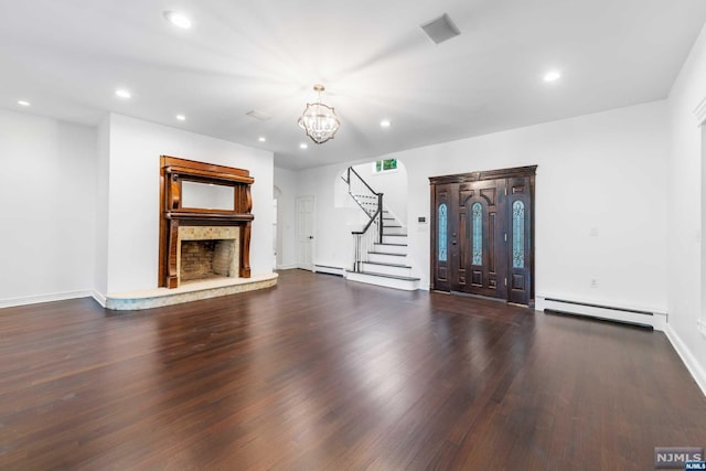 unfurnished living room featuring a notable chandelier, a stone fireplace, dark hardwood / wood-style flooring, and baseboard heating