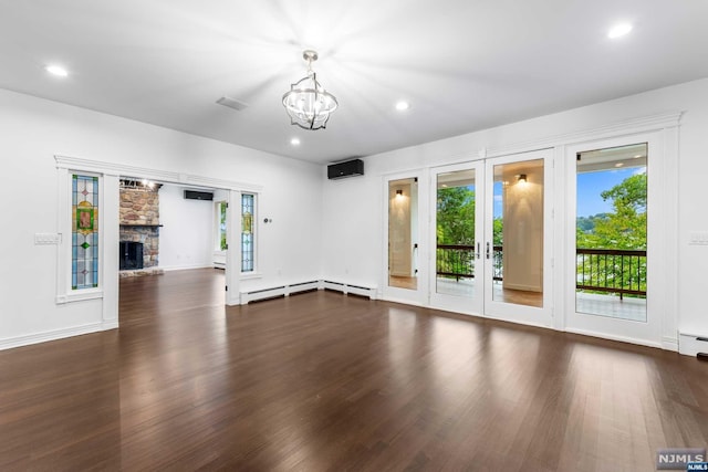 unfurnished living room featuring a stone fireplace, dark hardwood / wood-style flooring, a wealth of natural light, and a chandelier