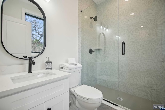 bathroom with vanity, toilet, and a shower with shower door