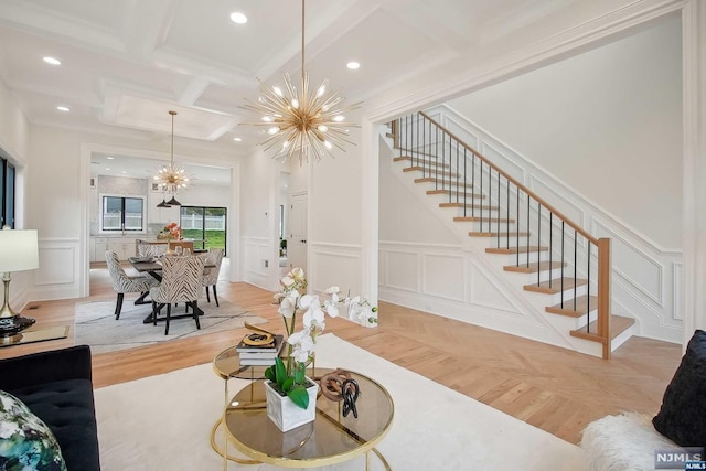 living room featuring coffered ceiling, beamed ceiling, a notable chandelier, light wood-type flooring, and ornamental molding