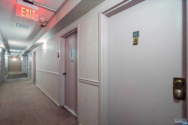 hallway with carpet and a textured ceiling