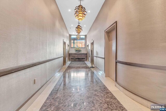 hallway featuring a towering ceiling and an inviting chandelier