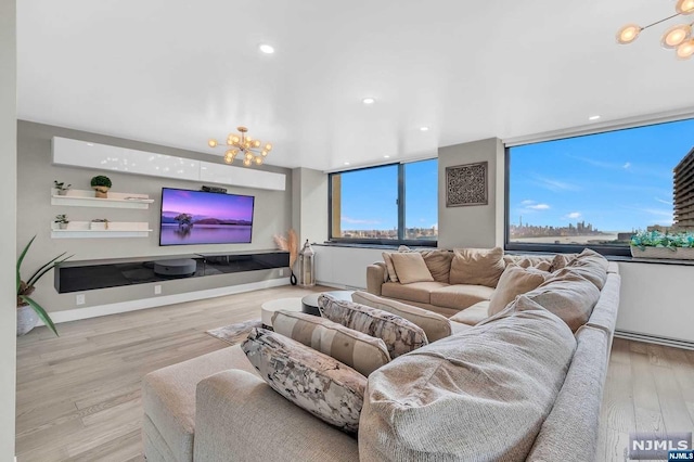 living room with a notable chandelier, a wall of windows, and light hardwood / wood-style flooring