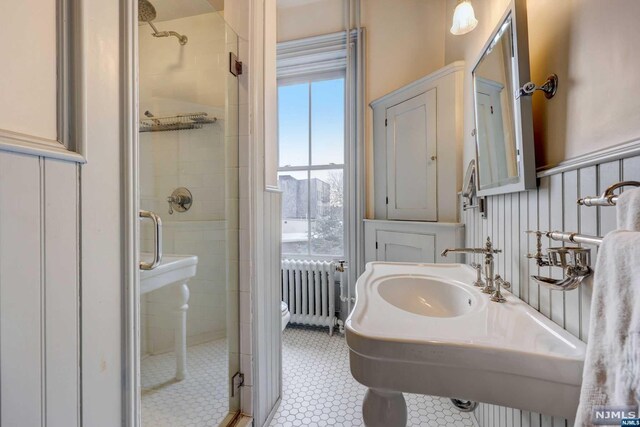 bathroom featuring tile patterned floors, radiator heating unit, and a shower with shower door