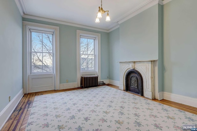 unfurnished living room with wood-type flooring, radiator, ornamental molding, and a notable chandelier