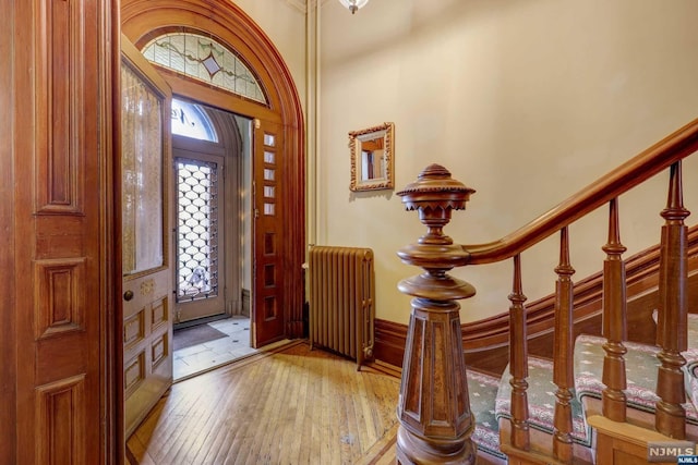 entryway featuring light wood-type flooring, a high ceiling, and radiator