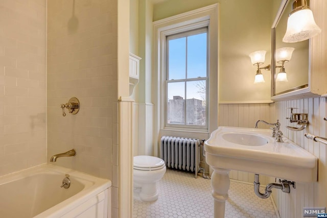 bathroom with tile patterned floors, a tub, radiator heating unit, and toilet