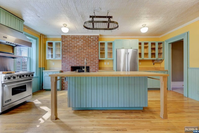 kitchen with a breakfast bar, appliances with stainless steel finishes, light wood-type flooring, and ornamental molding