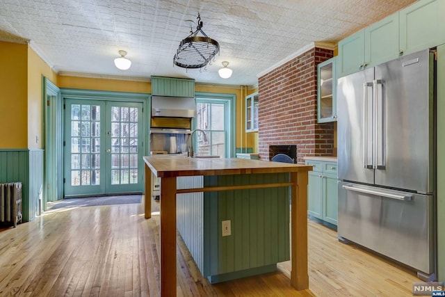 kitchen with sink, brick wall, light hardwood / wood-style floors, high end fridge, and ornamental molding