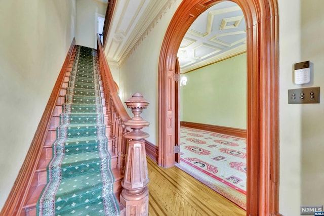 stairs featuring hardwood / wood-style floors, beam ceiling, crown molding, and coffered ceiling