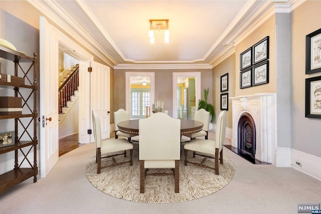 carpeted dining space featuring crown molding, a tray ceiling, and french doors