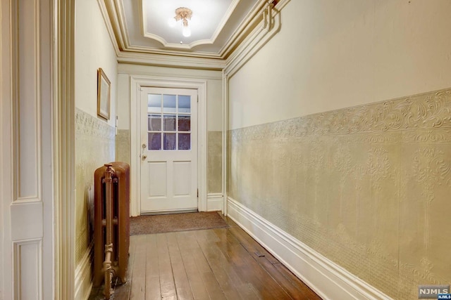 doorway featuring wood-type flooring, radiator heating unit, and crown molding