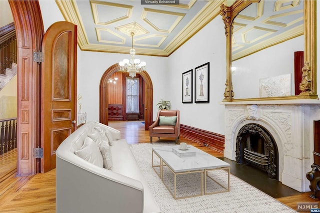 living room with wood-type flooring, an inviting chandelier, ornamental molding, and coffered ceiling