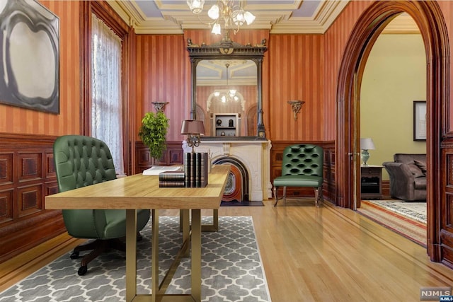 living area with light wood-type flooring, ornamental molding, and an inviting chandelier