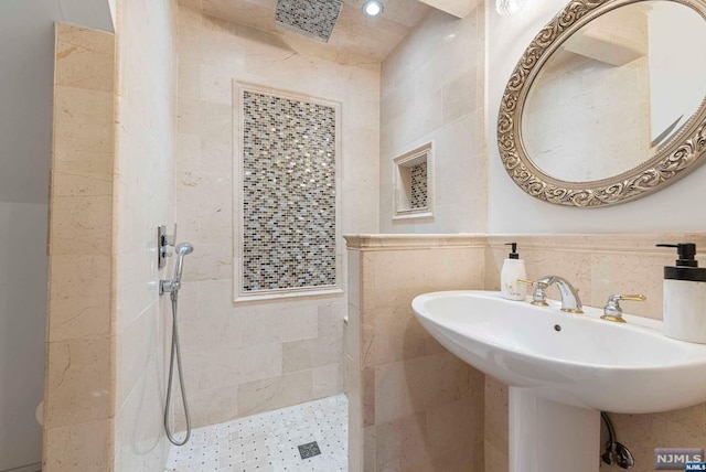 bathroom with a tile shower, tile walls, and sink