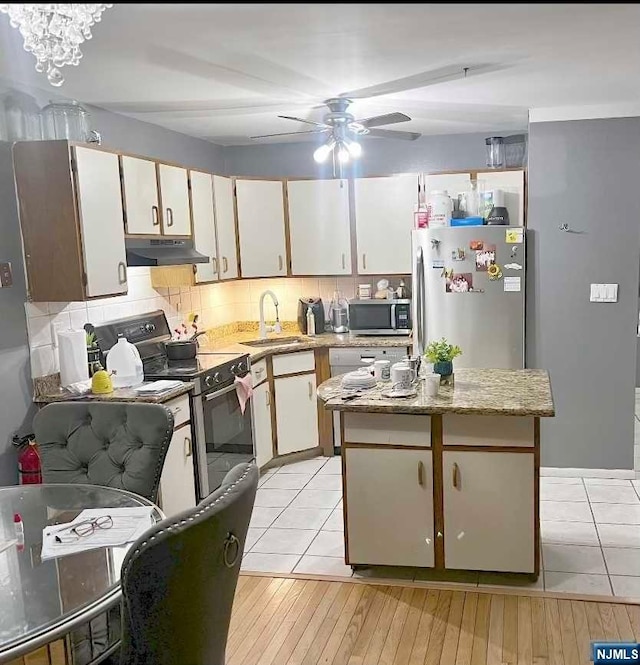 kitchen with sink, decorative backsplash, appliances with stainless steel finishes, light hardwood / wood-style floors, and white cabinetry