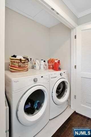 laundry area featuring dark hardwood / wood-style flooring, separate washer and dryer, and ornamental molding