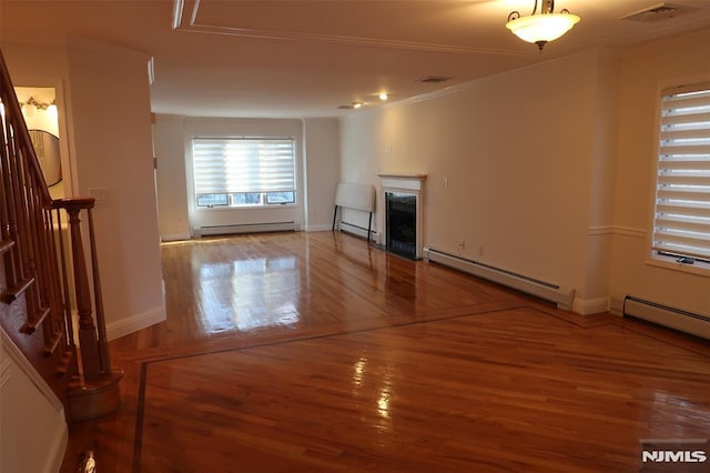 unfurnished living room featuring hardwood / wood-style floors, crown molding, and a baseboard heating unit