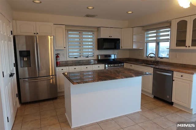 kitchen with sink, a center island, stainless steel appliances, light tile patterned floors, and white cabinets