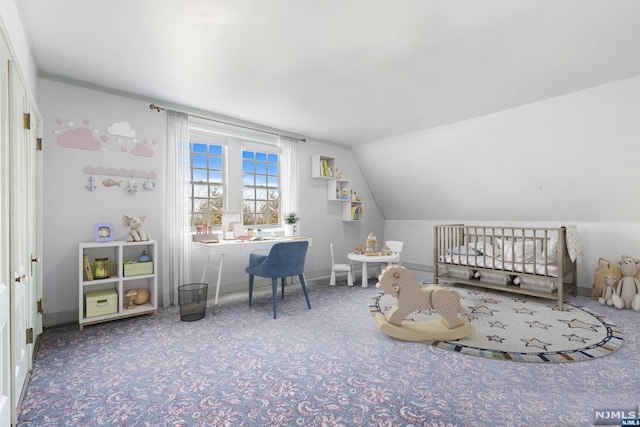 bedroom featuring lofted ceiling, a crib, and carpet floors