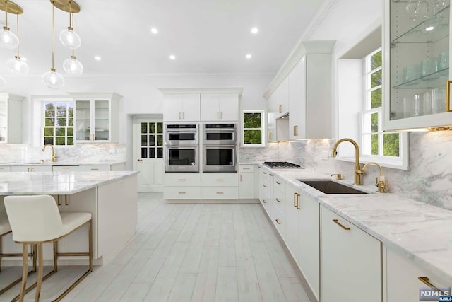 kitchen with backsplash, sink, light stone countertops, white cabinetry, and stainless steel appliances