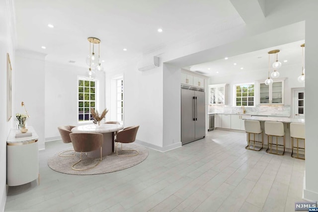 dining area featuring a wall mounted AC, sink, light hardwood / wood-style floors, and ornamental molding