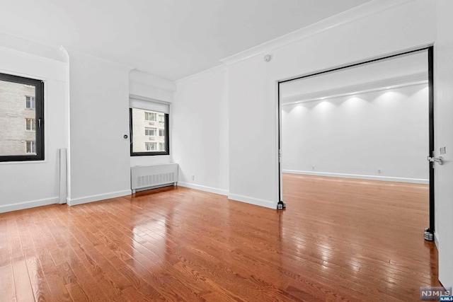 spare room featuring radiator, wood-type flooring, and ornamental molding