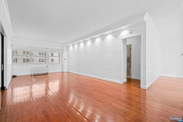 unfurnished living room featuring radiator heating unit and hardwood / wood-style floors