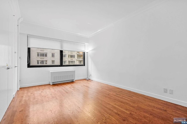 spare room with light hardwood / wood-style flooring, radiator, and crown molding