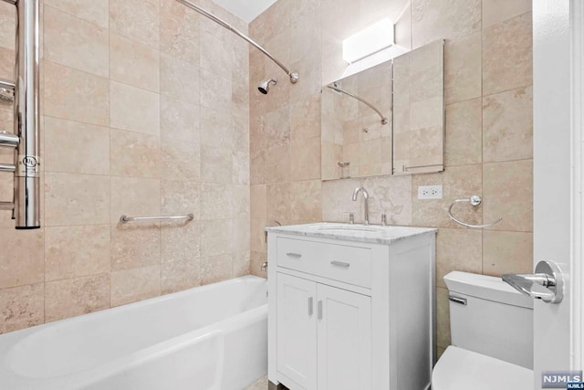 full bathroom featuring vanity, toilet, tile walls, and tiled shower / bath