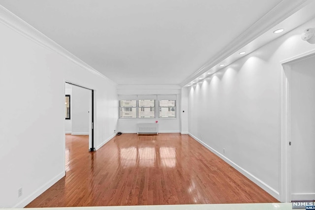 spare room with hardwood / wood-style floors, crown molding, and radiator