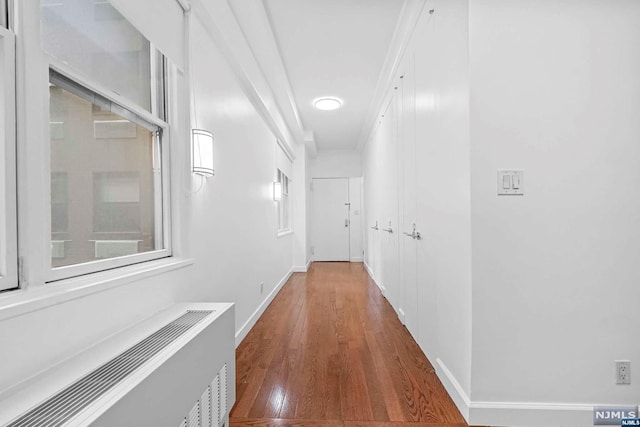 corridor with crown molding, wood-type flooring, and radiator heating unit