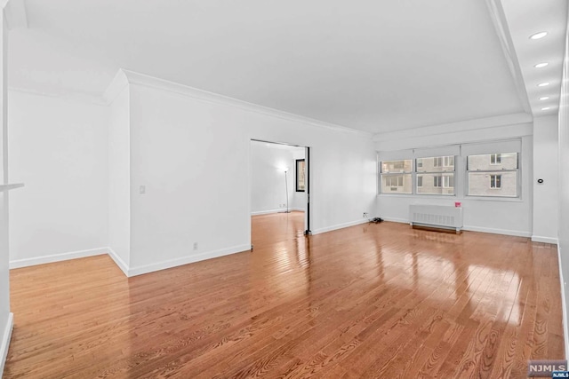 unfurnished living room with light hardwood / wood-style floors, crown molding, and radiator