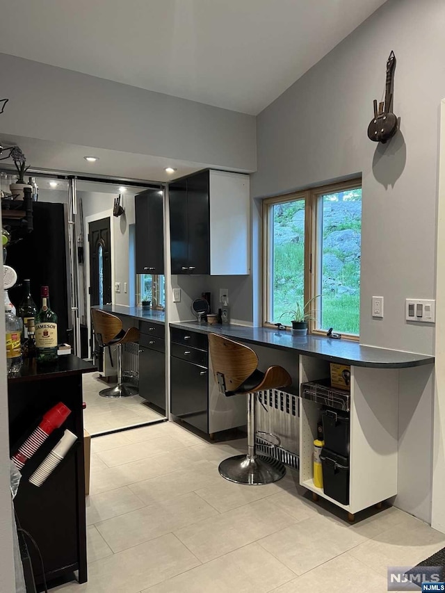 kitchen with light tile patterned floors, radiator heating unit, and vaulted ceiling