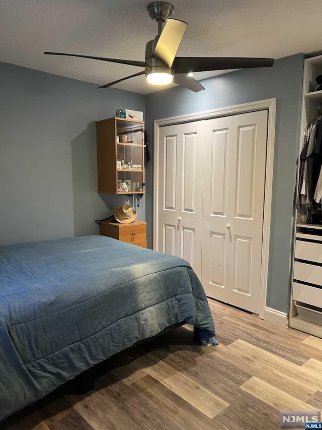 bedroom featuring ceiling fan, a closet, a textured ceiling, and light wood-type flooring