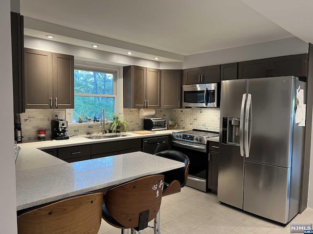 kitchen featuring sink, stainless steel appliances, backsplash, kitchen peninsula, and light tile patterned flooring