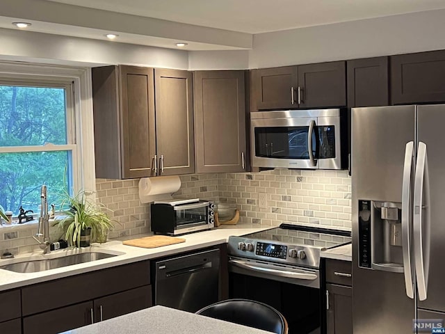 kitchen with appliances with stainless steel finishes, tasteful backsplash, a healthy amount of sunlight, and sink