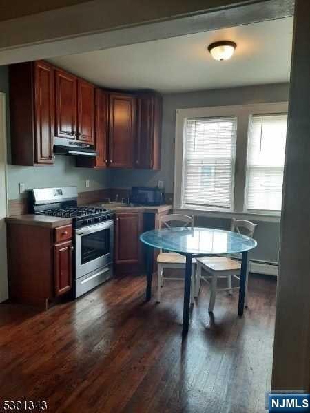 kitchen with baseboard heating, dark hardwood / wood-style floors, range hood, and stainless steel range with gas stovetop