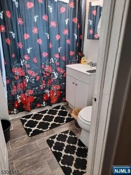 bathroom with wood-type flooring, vanity, and toilet