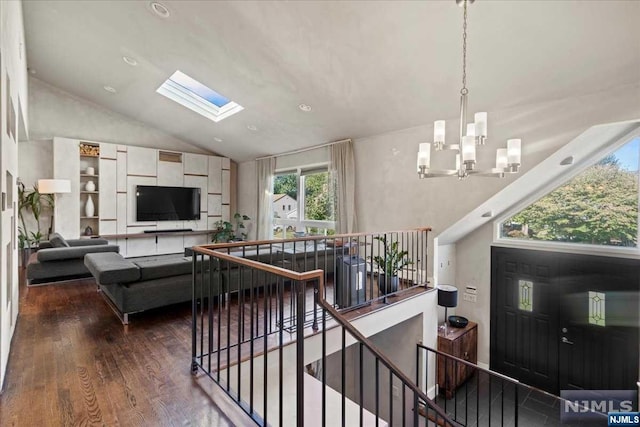 living room featuring high vaulted ceiling, hardwood / wood-style flooring, an inviting chandelier, and a skylight