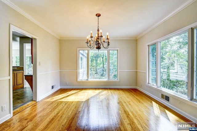 spare room with an inviting chandelier, light hardwood / wood-style flooring, and crown molding