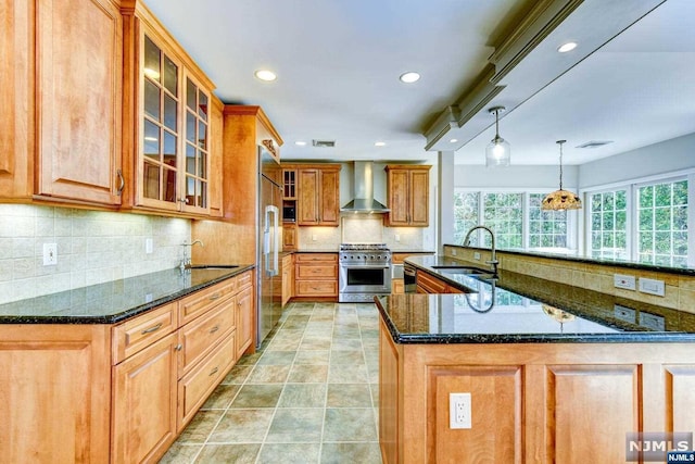 kitchen featuring dark stone countertops, sink, wall chimney exhaust hood, and high end appliances